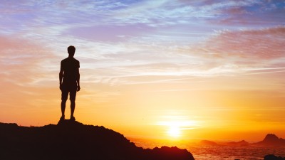 Man on cliff looking at sunrise